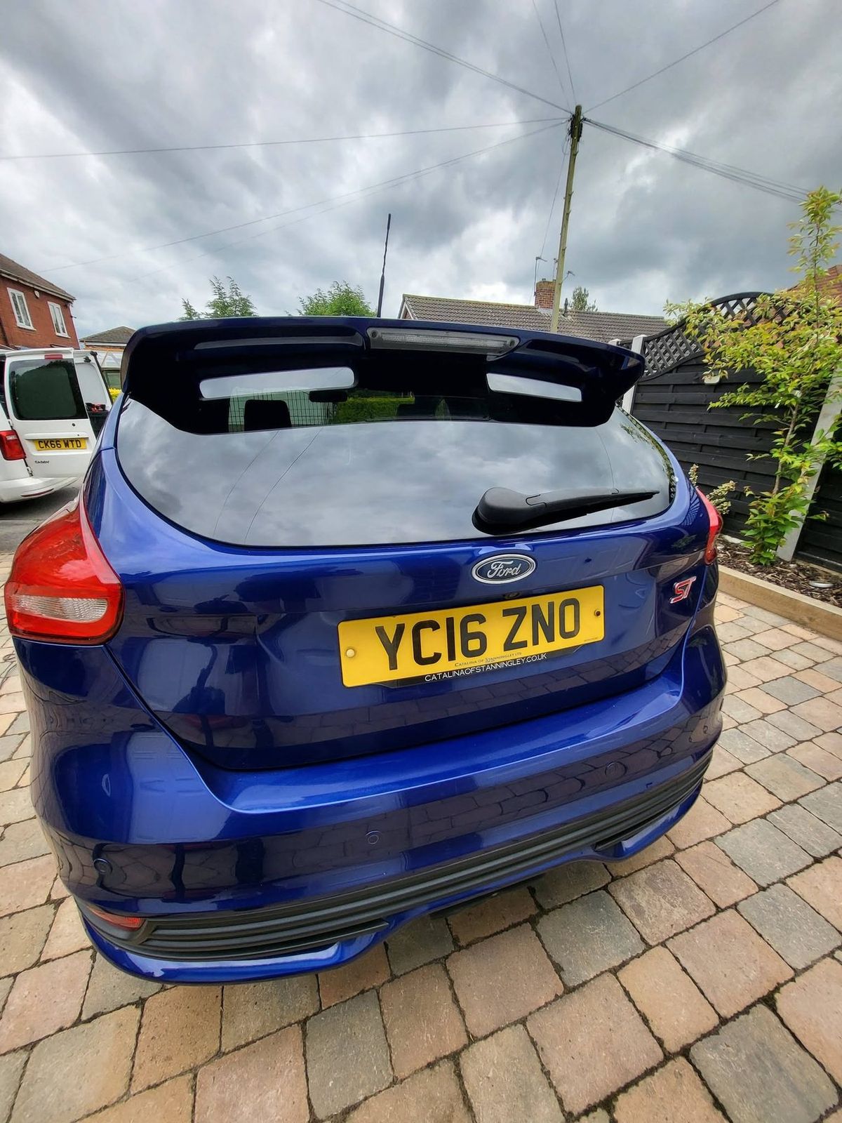 Tight crop of a blue hatchback's tailgate and spoiler after valeting, glass and paint both clear